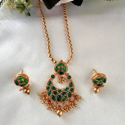 Gold necklace with green gemstones and matching earrings on a white background