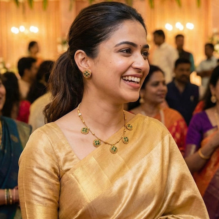 Woman in a gold saree smiling among other people at a festive event