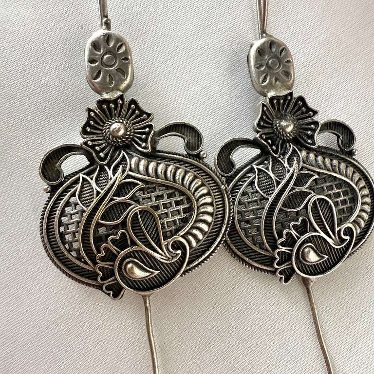 Pair of silver ear pins on a light gray background