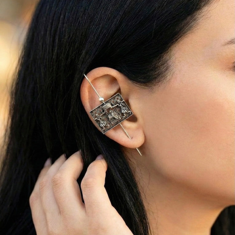 Close-up of a person wearing an ornate ear pin with a blurred background