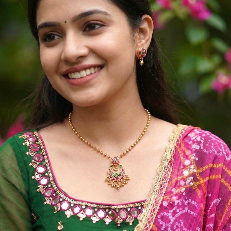 Woman wearing traditional jewelry and a colorful saree with a blurred floral background