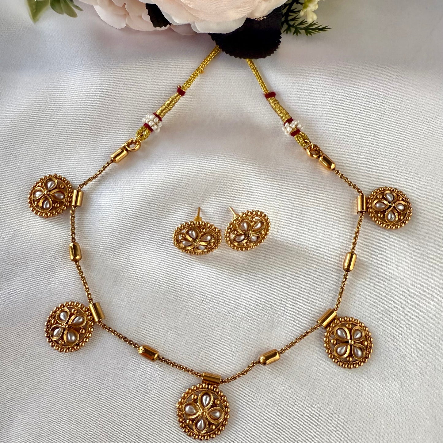 Gold necklace and earrings set with decorative elements on a white background