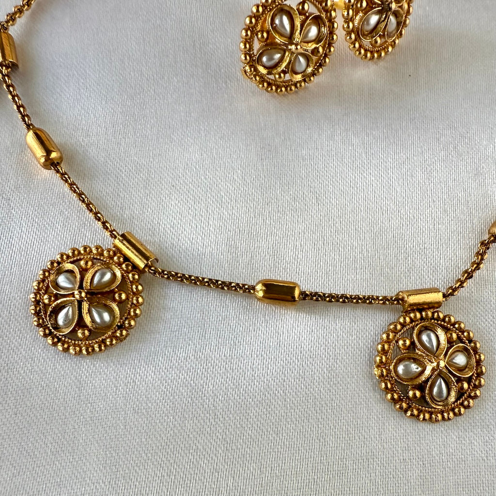 Gold necklace with floral pendants on a white background
