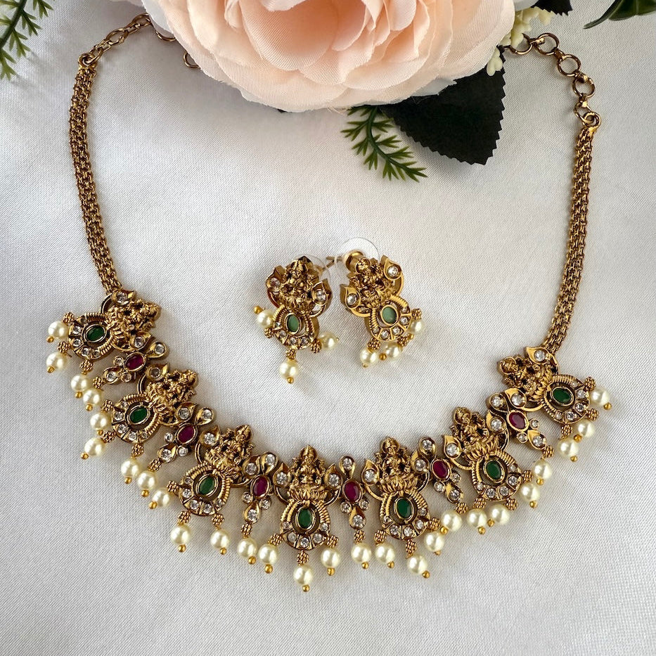 Gold necklace and earrings with gemstones on a white fabric background