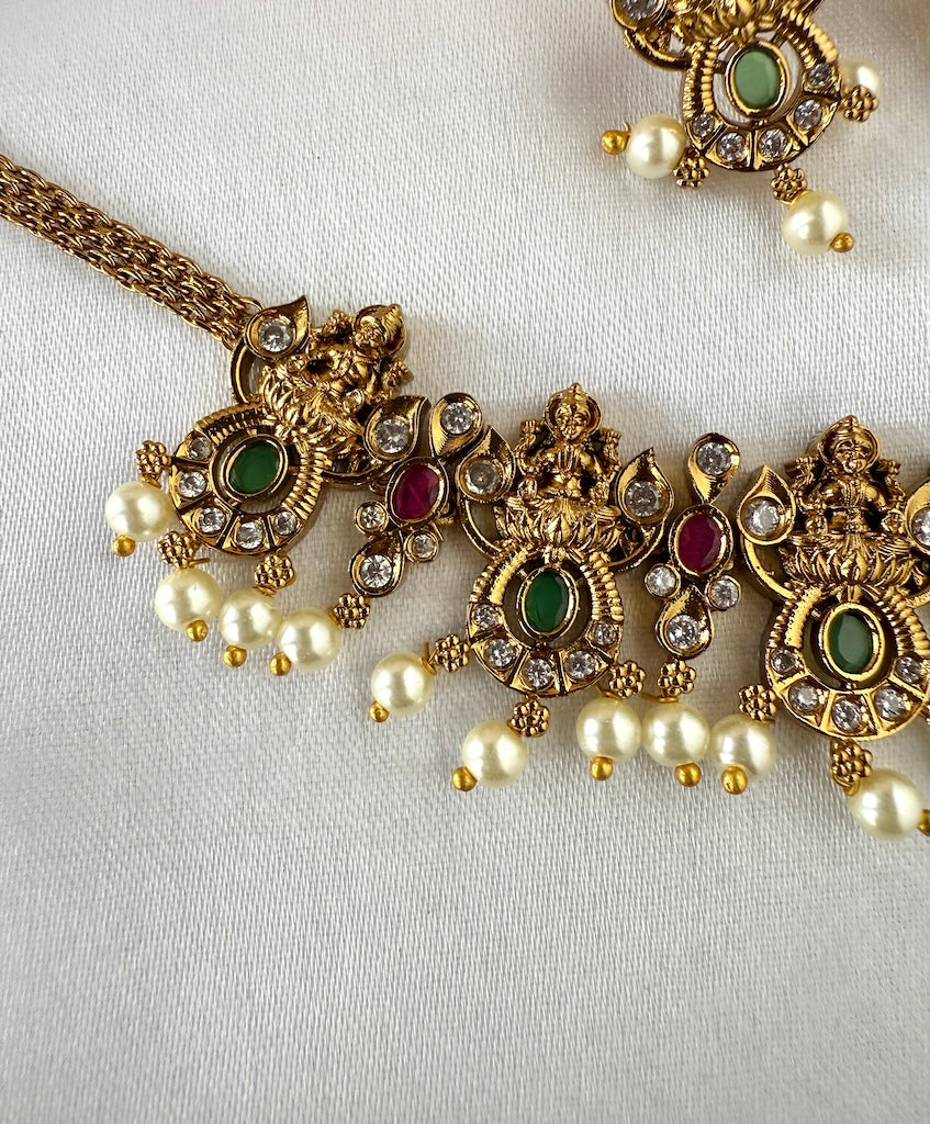 Gold necklace with pearls and gemstones on a white background