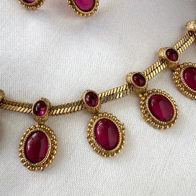 Gold necklace with red gemstones on a white background