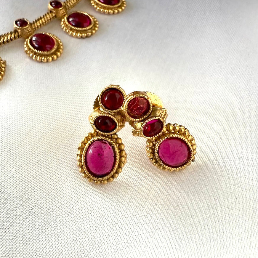 Gold earrings with red gemstones on a white background