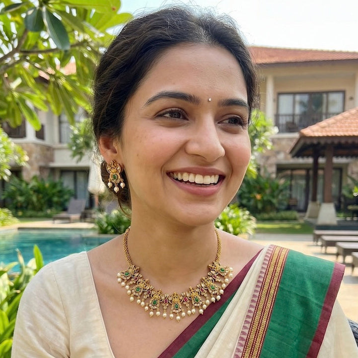 Woman in a green and cream saree with jewelry, sitting by a poolside.